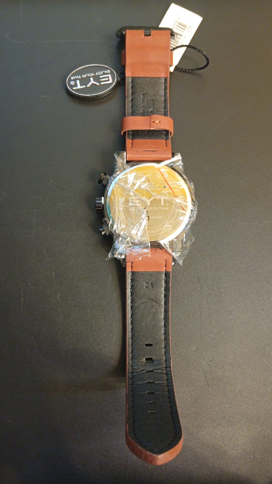 Reloj EYT, caja negra, esfera blanca, correa marrón.