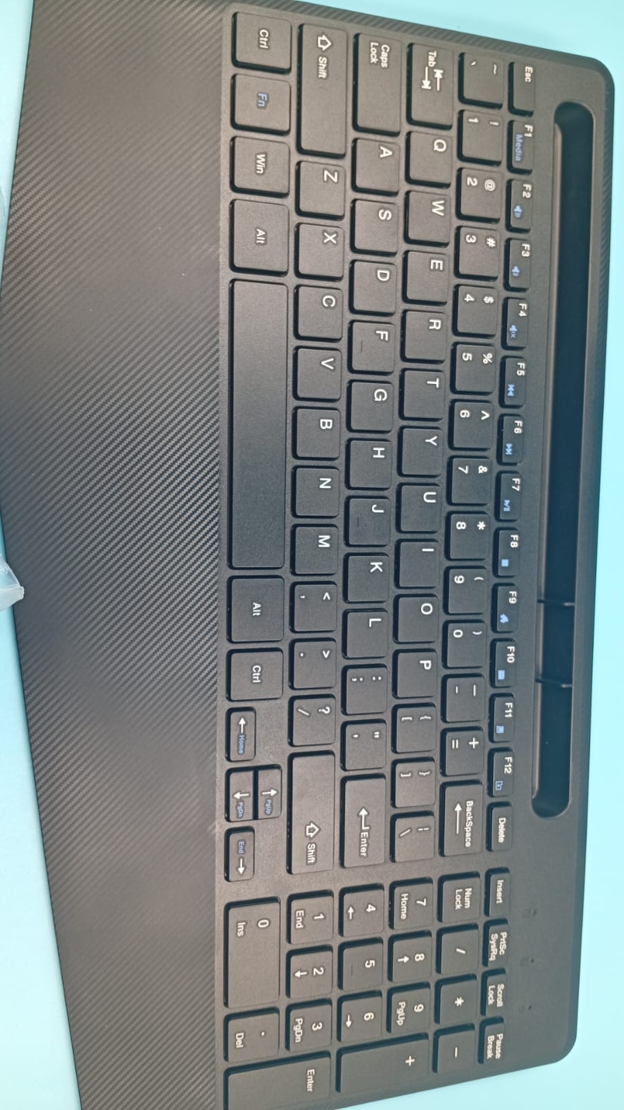 Teclado inalámbrico con reposamuñecas, ranura para teléfono o tablet.